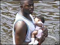 A man cradles a baby as he walks through floodwaters in New Orleans in the aftermath of Hurricane Katrina