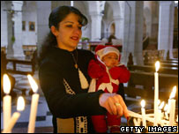Woman lights a candle at St Catherine's Church, Bethlehem